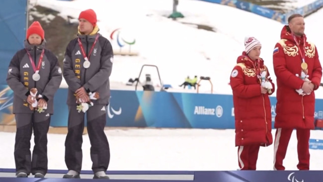 Niemieccy narciarze odwracają się plecami do Rosjanki na podium Zimowych Igrzysk Paraolimpijskich